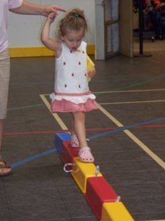 Adult Helping a Child Across a Balance Beam